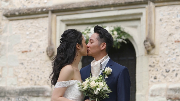 A bride and groom kissing in front of a church
