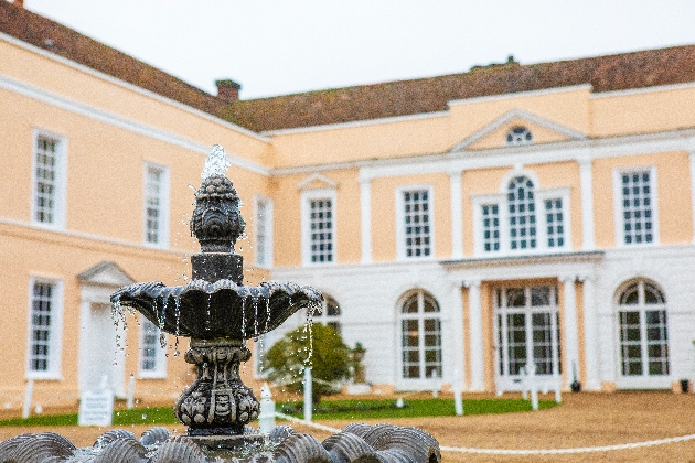 The exterior of a large house with a water fountain in front of it