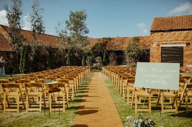 A courtyard decorated with chairs with a welcome sign at the start of the aisle