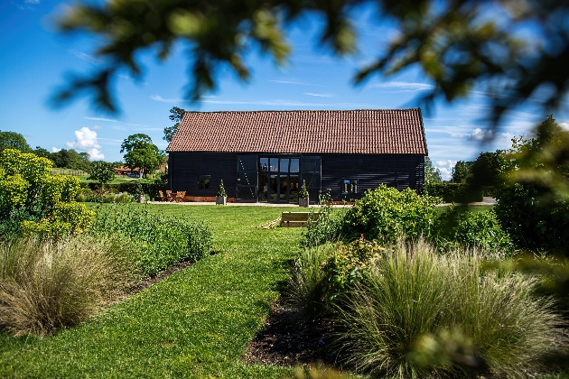 A black wooden barn surrounded by manicured grounds