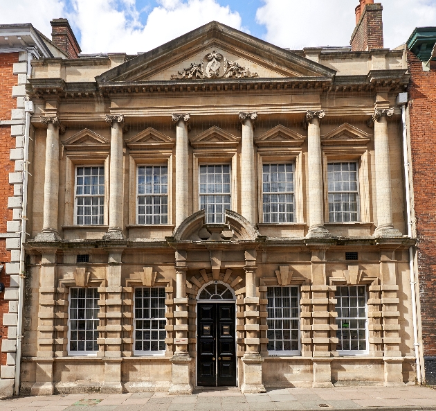 The exterior of a large Georgian building with columns and detailing