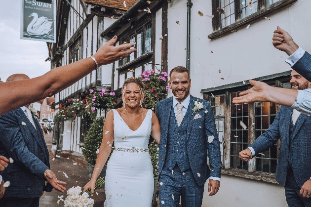 A bride and groom walking through a tunnel of confetti