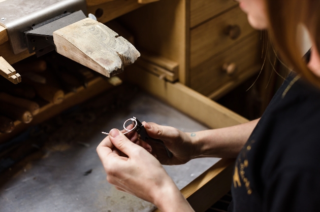 A woman bending a piece of metal into a ring shape