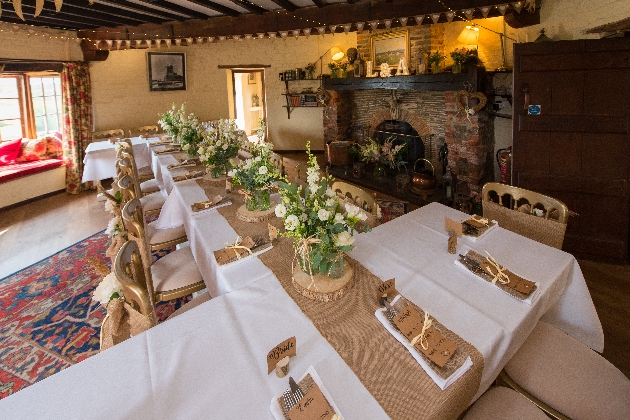 Several tables put together and decorated with a white table cloth and flowers