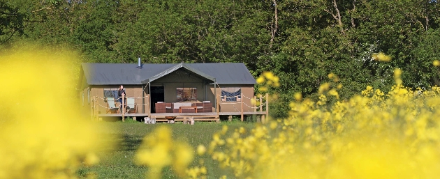 The exterior of a glamping tent with a woman standing outside of it