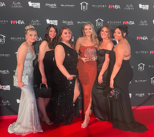 Six ladies in nice dresses holding an award