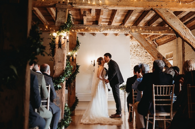 A bride and groom kissing at the end of an aisle