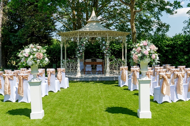 A gazebo decorated with flowers and surrounded by white chairs