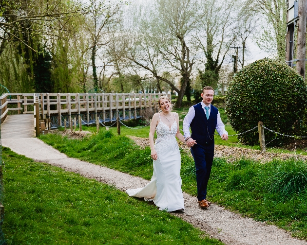 A bride and groom walking on a path surrounded by grass