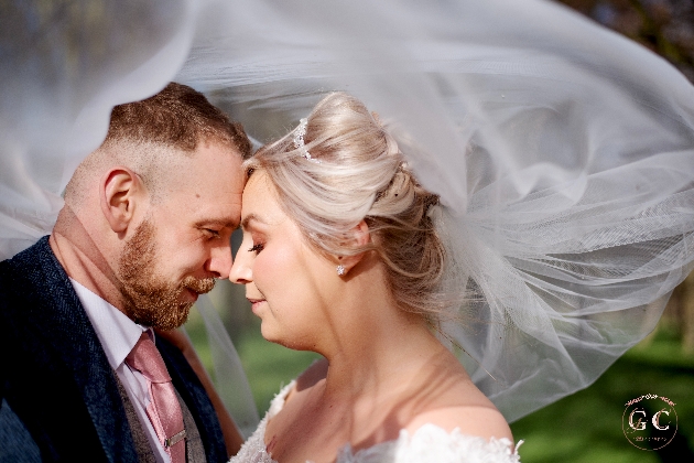 A bride and groom underneath a veil