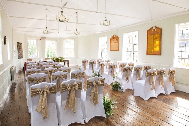 A light-filled room with white chairs decorated with gold bows