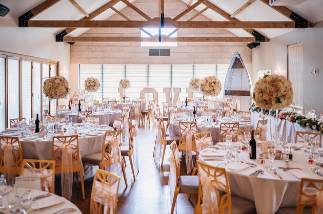 A light-filled room decorated with round tables and flowers