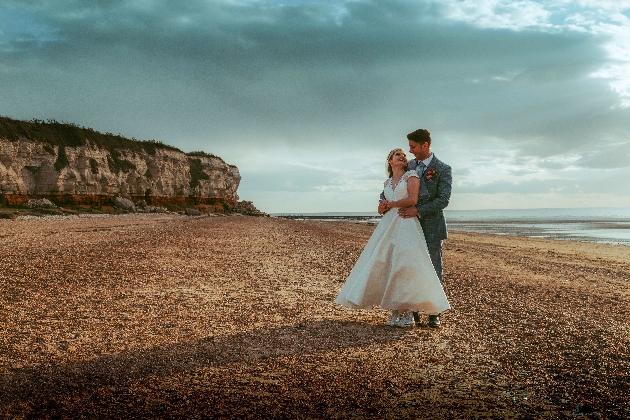 A bride and groom embracing on the beach