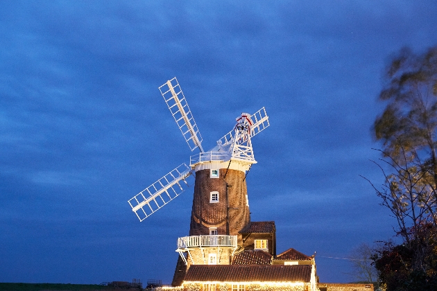 The exterior of a windmill decorated with lights