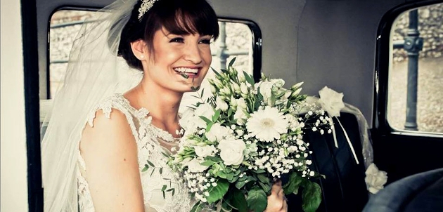 A bride in a car holding a white bouquet