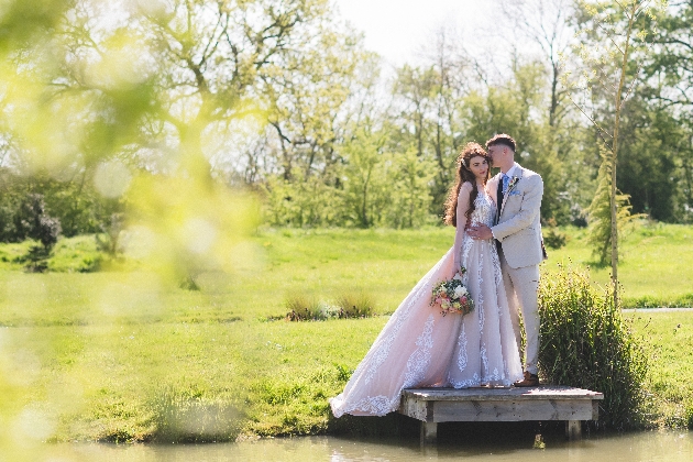 A bride and groom embracing next to a pond