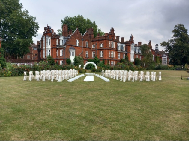 An outdoor ceremony set up on the grass in front of a grand building