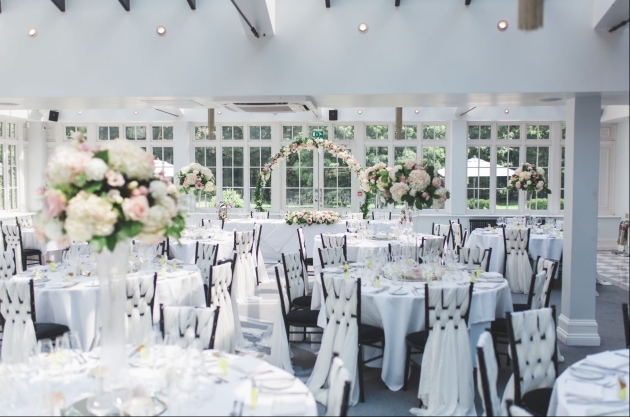 A light room filled with round tables and flowers