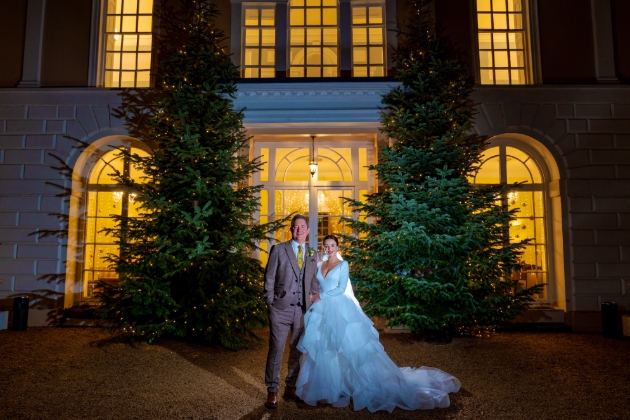 A bride and groom standing in front of two large Christmas trees