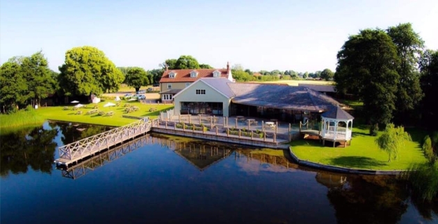 A birds eye view of a white building with a bridge that goes over a lake